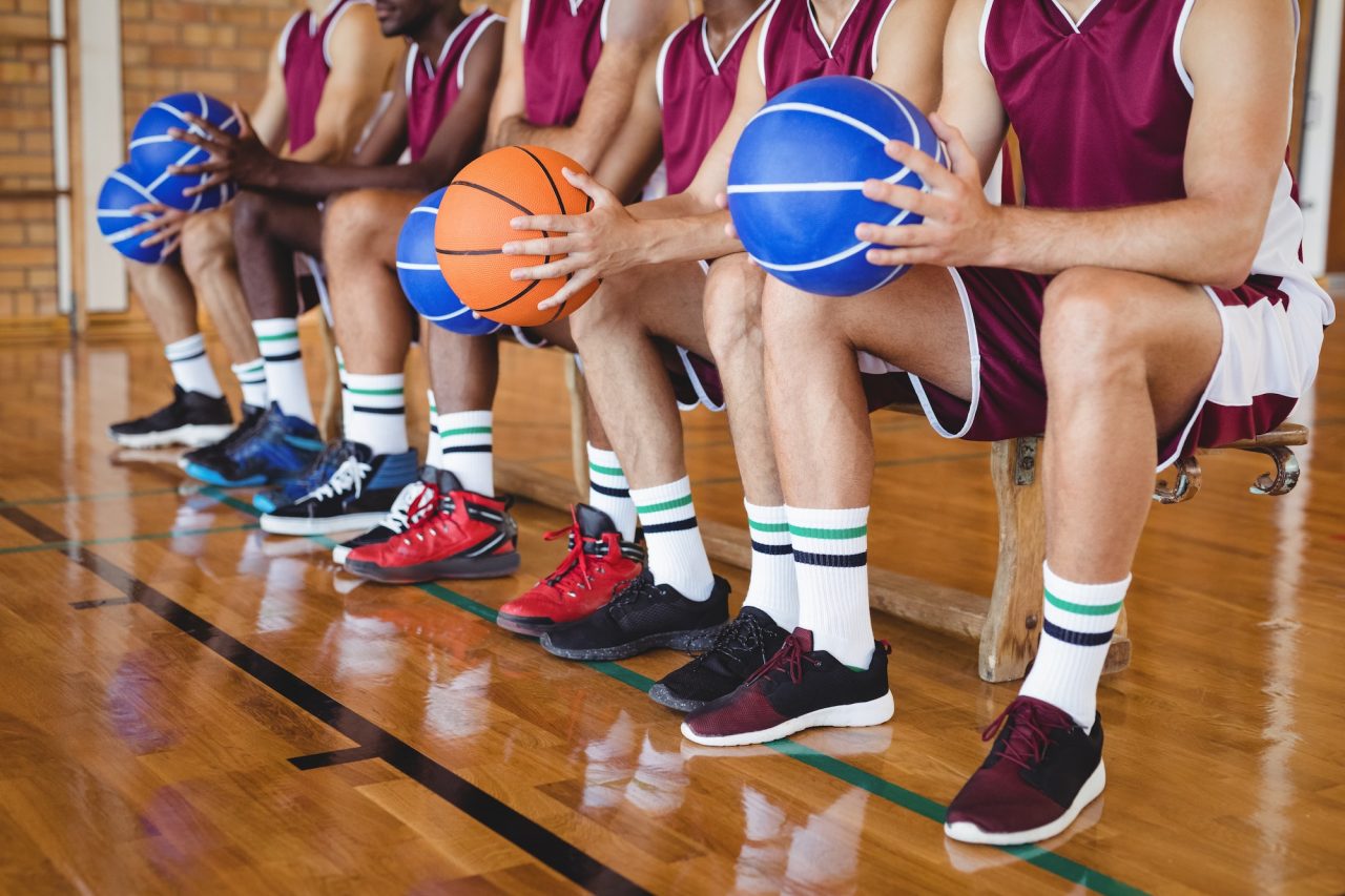 Basketball players sitting on the bench with a basketball.