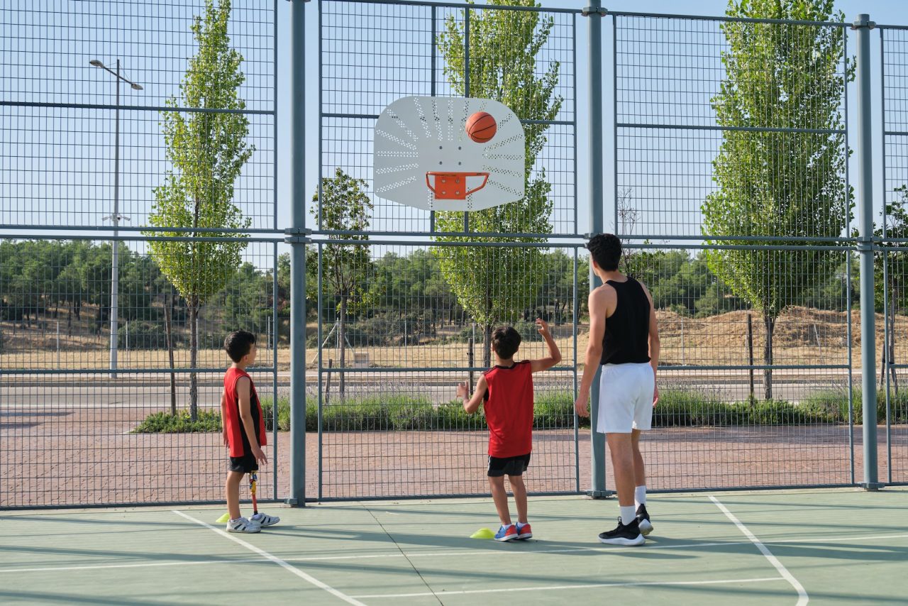 Basketball trainer showing two children how to shoot a basketball.