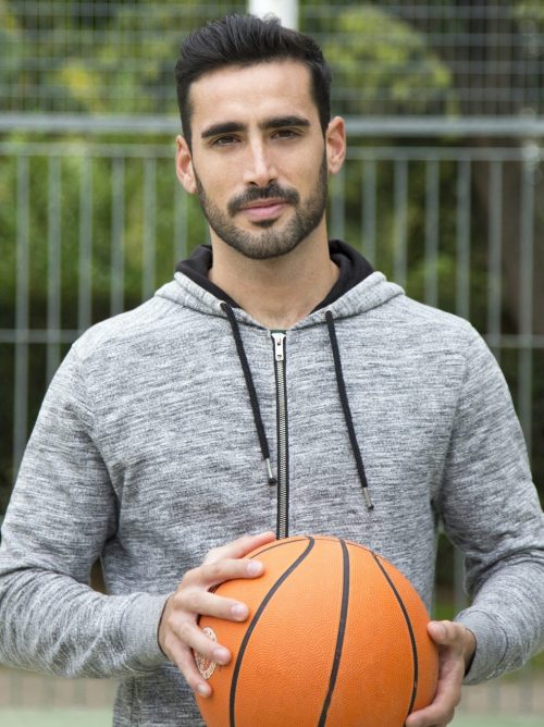 Male coach standing with a basketball on the court.